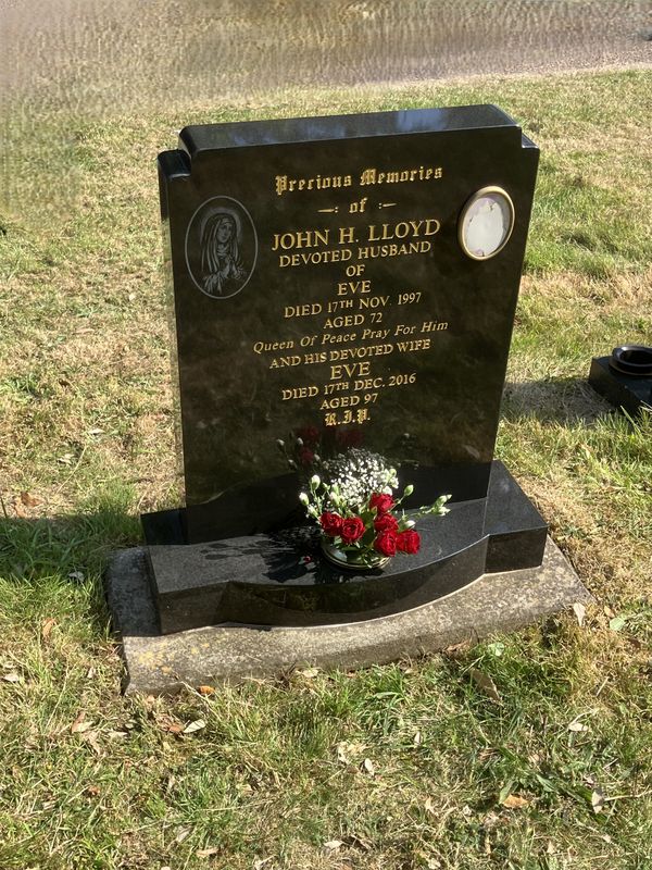 Upright granite headstone with fresh red roses after a Calon visit